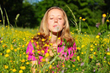 Beautiful woman blows away dandelion