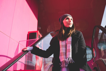 young woman outdoor on escalator moving downward looking away pensive - getting away from it all, thinking future, traveller concept