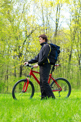 Fototapeta premium Man Cyclist with Bike and Backpack among the green nature