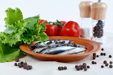 Anchovy fish on a plate with herbs, branch of tomatoes and spicy