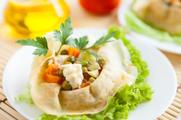 Salad with cooked vegetables wrapped in a pancakes on a plate