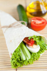 Fresh vegetables with egg in tortilla on bamboo mat