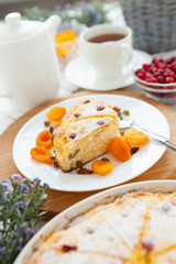 Cheese pie with tea, dried apricot and raisins closeup on a plate
