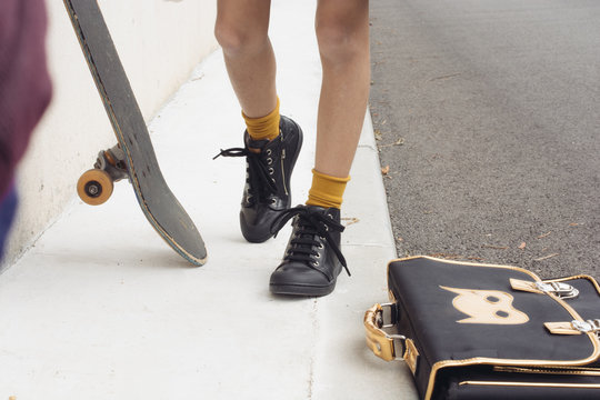 sneakers petite fille avec cartable et skate sur le trottoir