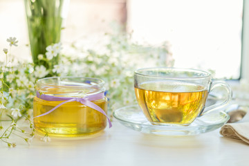 Honey in glass jars and cup of tea