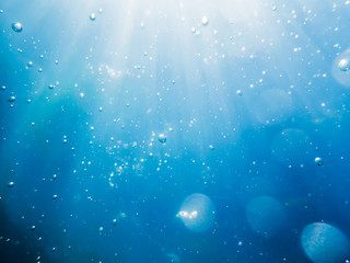Bubbles underwater in sea and sun rays. Water texture in ocean