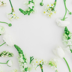 Frame pattern made of white flowers - ranunculus, snapdragon and tulip on white background. Background of flowers. Flat lay, top view.