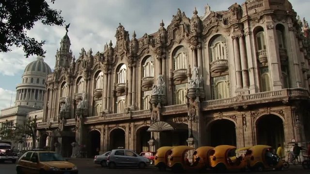 Tilt down Gran Teatro de la Habana to a row of parked cococabs. Havana Cuba