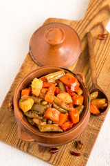  Vegetable stew. Stewed vegetables in a clay pot on a wooden cutting board.