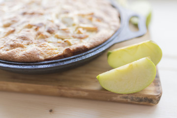 Freshly baked apple pie in baked dish and apple slices