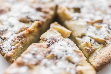 Apple pie and sliced piece of pie in powdered sugar, close-up view