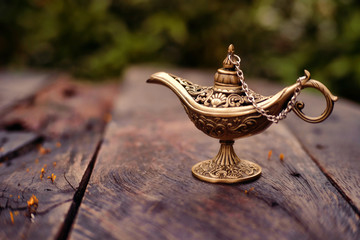 Close up of gold decorated magic lamp on wooden background.