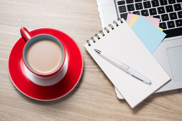 Blank white notebook open, pen and cup of coffee on the desk