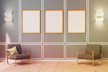Three framed posters on gray wall, armchairs toned