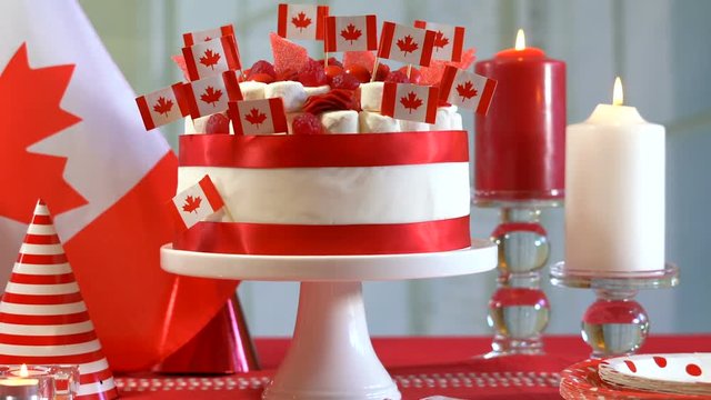 Happy Canada Day party table with red and white cake decorated with maple leaf red Canadian Flags, marshmallows and candy, dolly reveal.