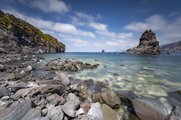 Fototapeta na wymiar Baia rocciosa con vista sul faraglione e le isole di Lipari e Salina dietro, isola di Vulcano IT