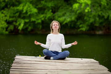 Fototapeta na wymiar Meditating girl on the pier