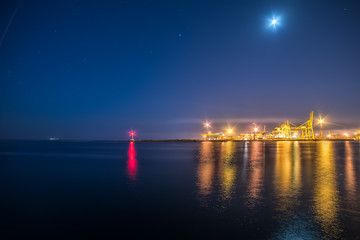 A view of the port facilities, a small lighthouse at the entrance to the port. Night photo.

