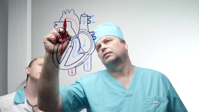 The surgeon draws on clear glass with a marker the human heart.