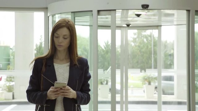 Woman using smartphone to text message in lobby