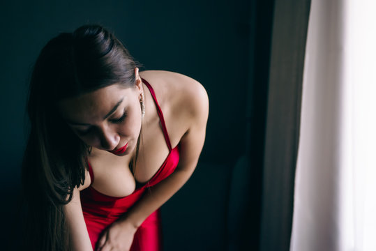 Sexy gorgeous beautiful girl standing in  room with red dress, elegant hair-style and make-up