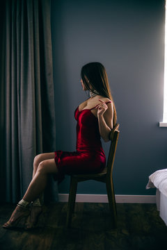 Sexy gorgeous beautiful girl sit  in  room with red dress, elegant hair-style and make-up