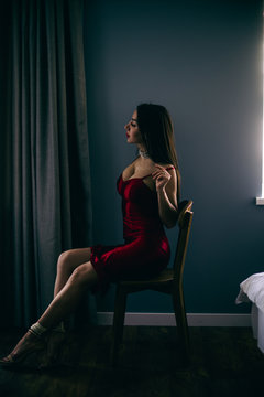 Sexy gorgeous beautiful girl sit  in  room with red dress, elegant hair-style and make-up