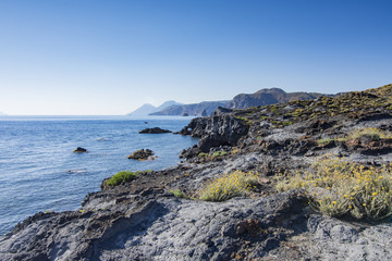 Fototapeta na wymiar Scogliera di roccia vulcanica con vista su Lipari e Salina sullo sfondo, isola di Vulcano - arcipelago delle Isole Eolie IT