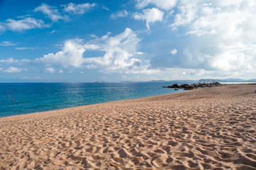 Fototapeta na wymiar Empty sandy beach illuminated by the sun on the island of Sardinia.