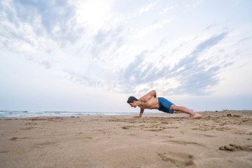Fototapeta na wymiar Fitness man doing push-up exercise on beach.
