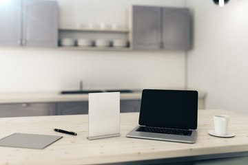 Blank laptop in blurry kitchen