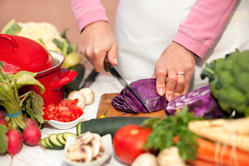 Housewife slicing red cabbage on slices in the kitchen
