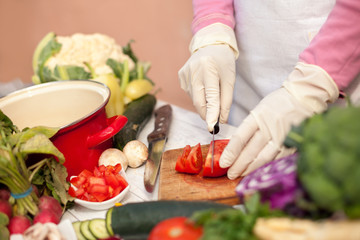 Female with gloves cutting tomato