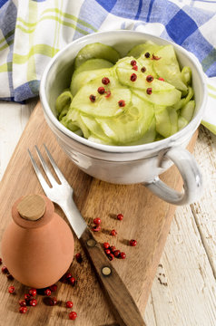 cucumber salad in a grey cup  on wooden board