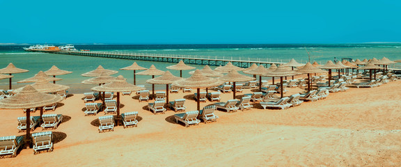 Chaise lounge and parasols on the beach against the blue sky and sea. Egypt, Hurghada © KAL'VAN