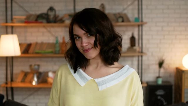 portrait of young cute and enamored woman with dark hair smile flirty and glancing with shy to the camera