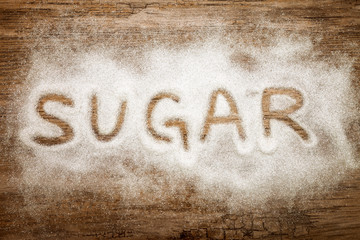 Word sugar written on wooden surface, high sugar level and diabetes concept