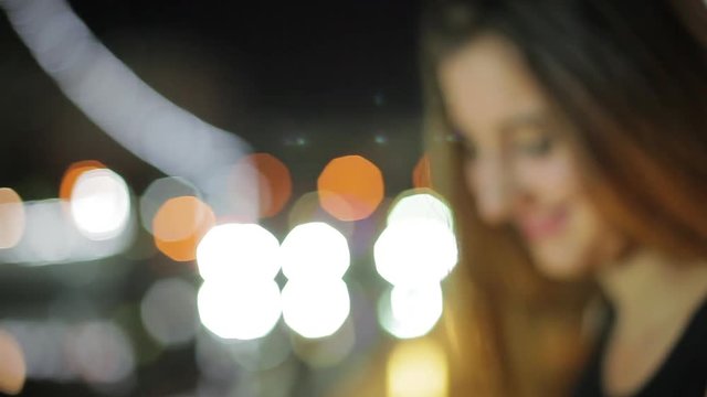 Teenage girl looking at night view and then turning to smile at person out of frame