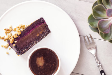 Hot coffee and slice of healthy raw chocolate mousse cake on white plate. Vegan gluten, dairy free dessert