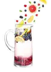 Falling fruit slices and berries into glass jug with lemonade on white background. Recipe for summer drink
