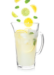 Falling fruit slices into glass jug with lemonade on white background. Recipe for summer drink