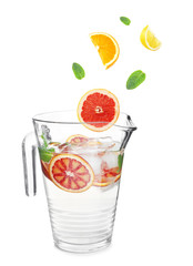 Falling fruit slices into glass jug with lemonade on white background. Recipe for summer drink