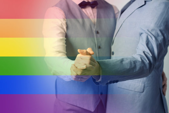 Happy gay couple dancing against color background