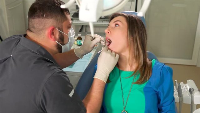 Woman at the dental clinic. Man dentist providing initial examination of the patient to define the teeth problems