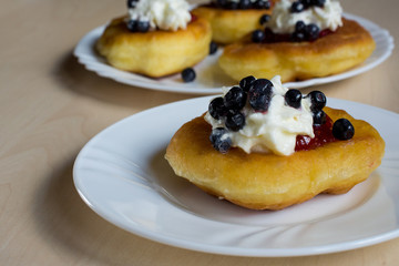 Sweet homemade donuts with jam and whipped cream and blueberries