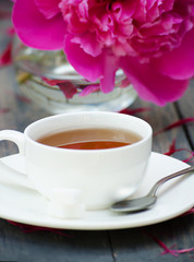 Hot tea and peony petals on dark