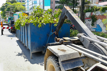 Garbage container latch with truck full of garden refuse woods