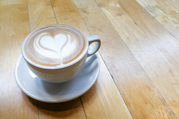 Cappuccino foam art with love heart shape on table