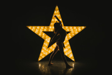 The girl is dancing against the backdrop of a glowing star - obrazy, fototapety, plakaty