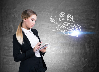 Serious blond woman with a notebook and brain bulb